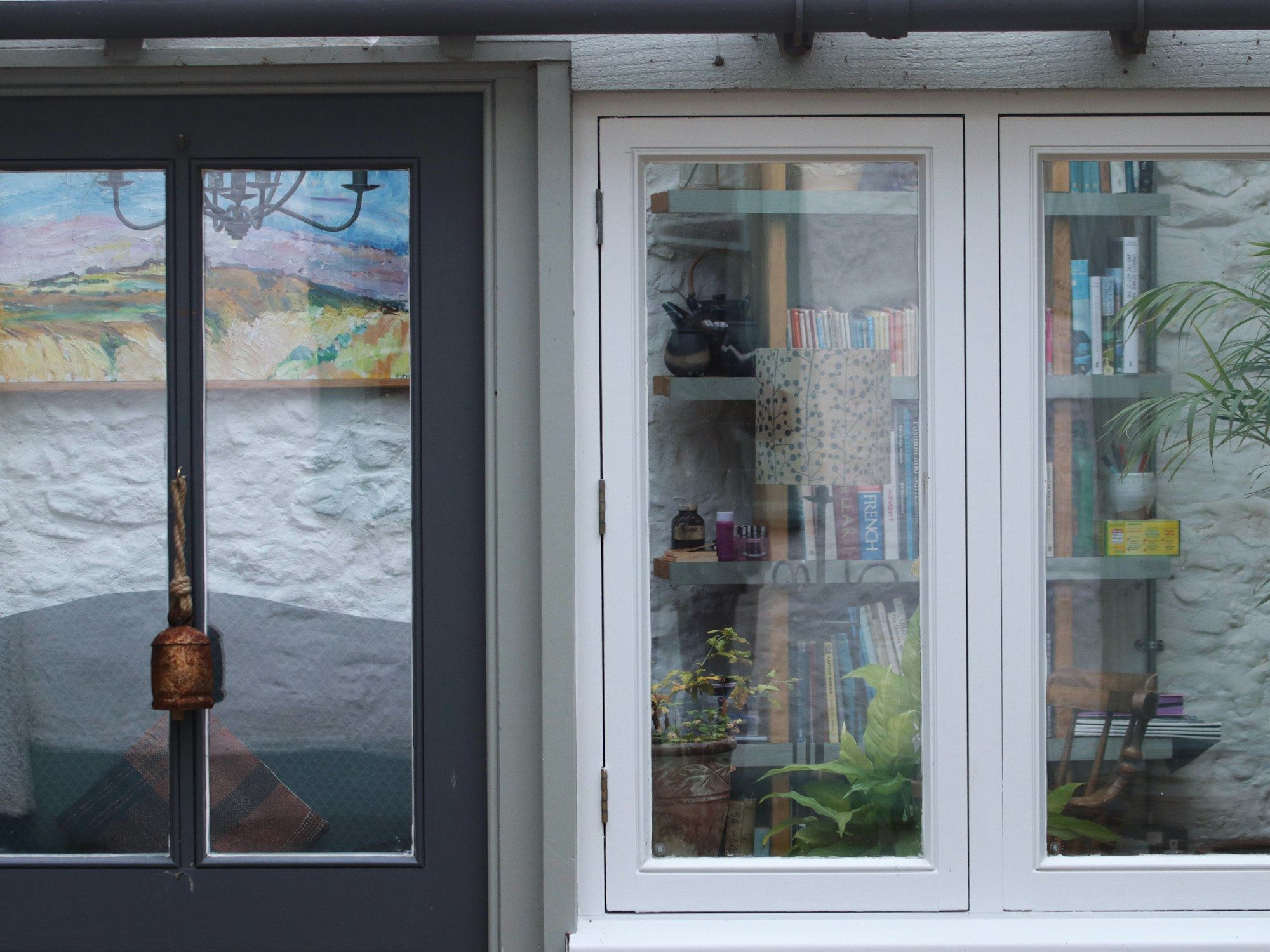 Dark door beside a window filled with books and plants.