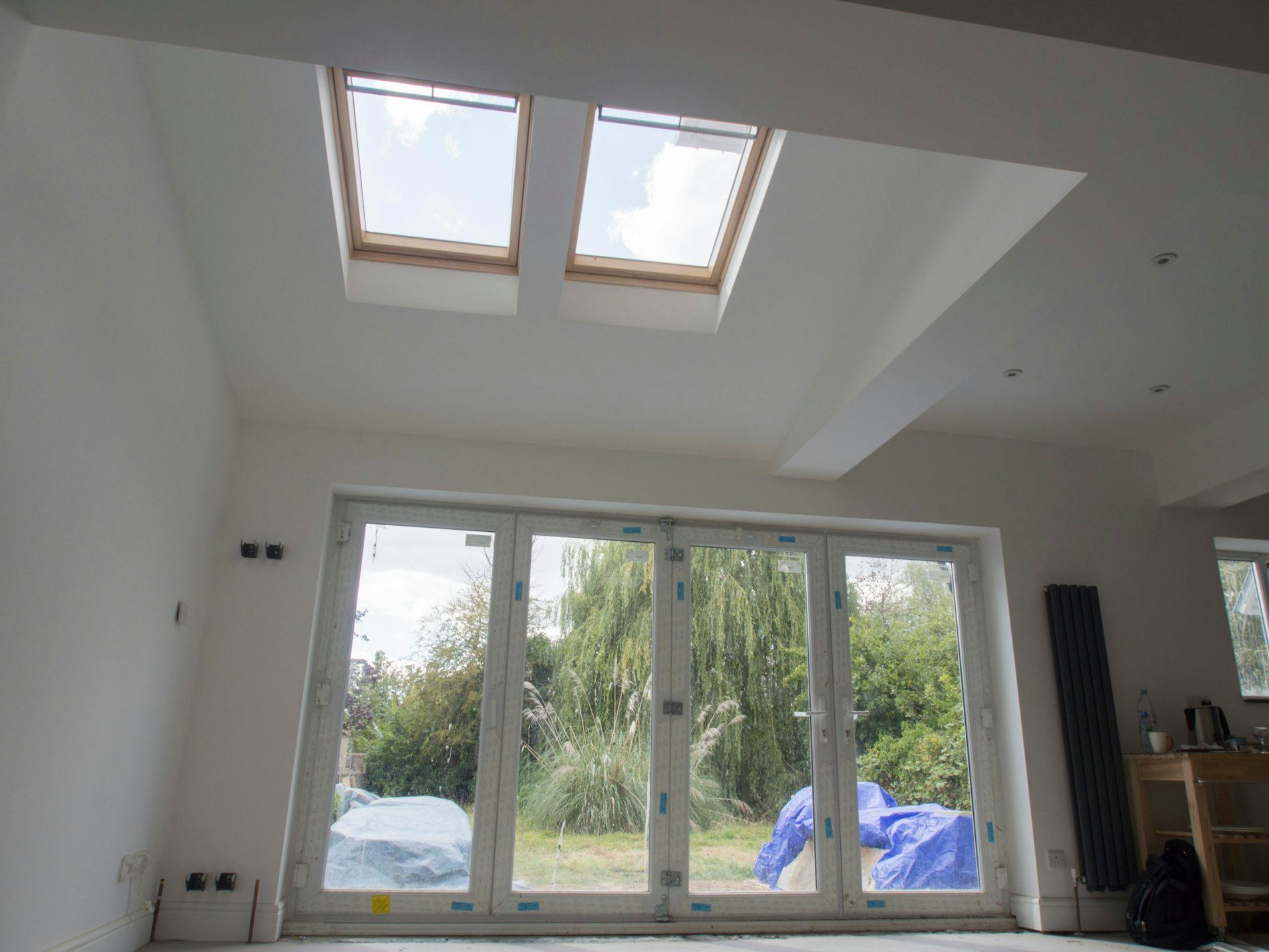 Bright room with skylights and bifold doors opening to a garden.